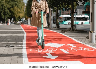 traffic, city transport and people concept - woman riding electric scooter along red bike lane with signs of bicycles and two way arrows on street - Powered by Shutterstock