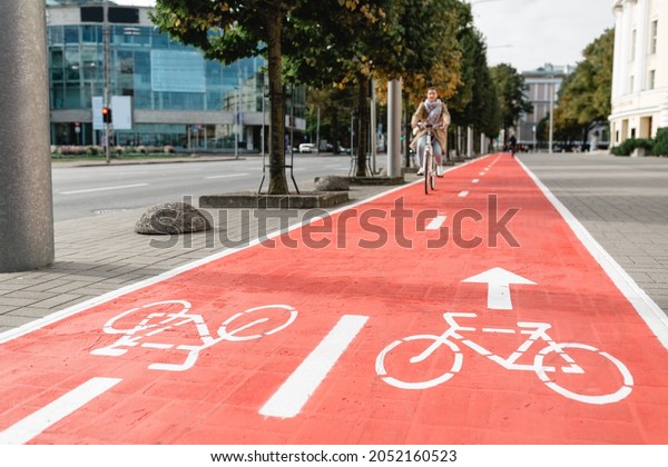 traffic, city transport and people concept - woman\
cycling along red bike lane with signs of bicycles and two way\
arrows on street