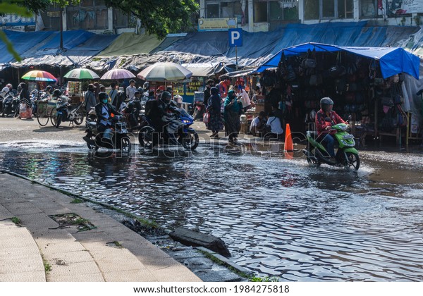 Traffic conditions of vehicles on a flooded\
road, people\'s activities in front of a traditional market,\
Tasikmalaya, West Java, Indonesia, June 2,\
2021