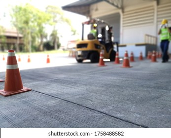 Traffic Cone Put On Cement Floor With Blurred Background Of Fork Lift In Driver Training Area, Outdoor Forklift Training Class In Factory 