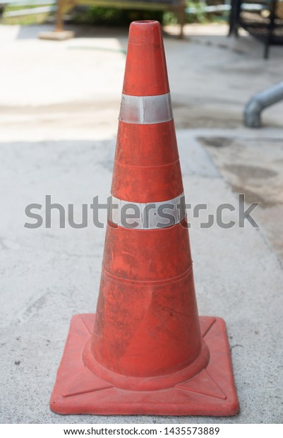 traffic cone, with white and orange stripes on gray\
asphalt, copy space