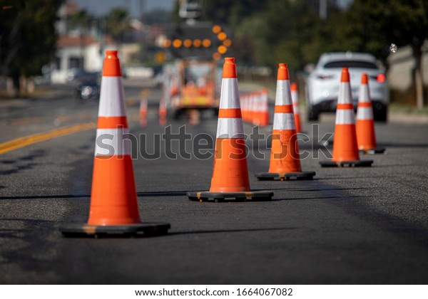 Traffic cones on road\
with electronic arrow pointing to the right to divert traffic and\
white car in distance