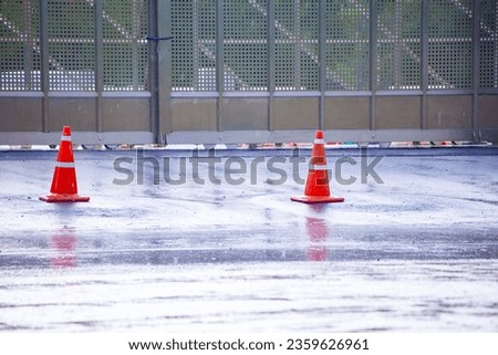 Traffic cones placed on the road during rain. Showing signs of slippery roads due to flooding.