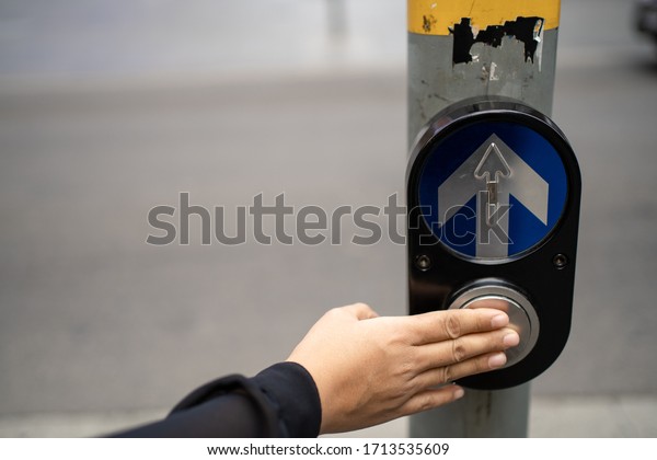 Traffic control.\
woman presses a finger on the button in front of a traffic light to\
safely cross a road. Close\
up.