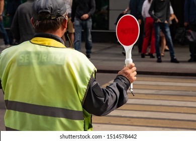 traffic controller with a stop sign helps pedestrians cross the road - Powered by Shutterstock