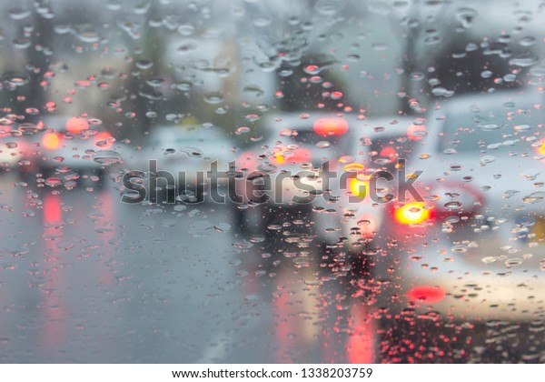 traffic dimly light in front of window with raindrops ,\
blurred light , traffic on the road in the city , colorful bokeh if\
traffic lights. 