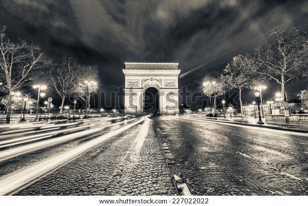 Traffic flow in Paris. Car light trails in\
front of Arc de\
Triomphe.