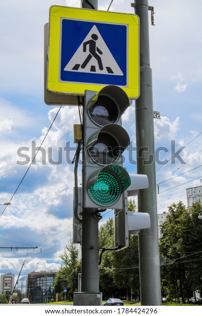 Traffic light with a burning green signal\
and a pedestrian crossing sign against the blue sky. Traffic\
safety, urban traffic regulation. Vertical\
image.