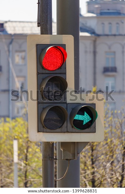 Traffic light with forbidding red signal and\
permissive green signal of right arrow section on city street in\
sunny day closeup