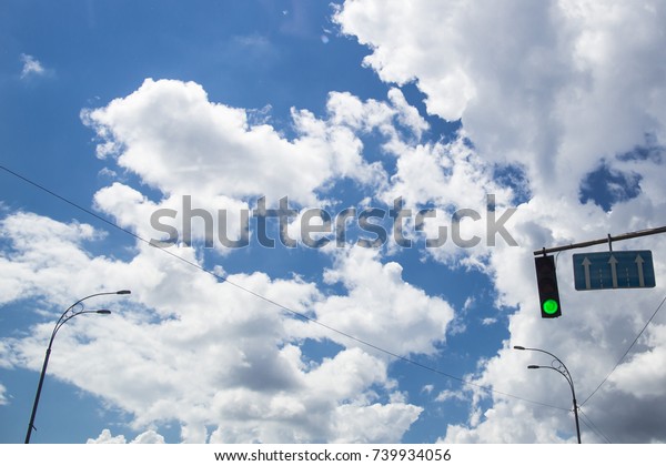 traffic light is green - traffic is allowed.\
against a blue sky with white\
clouds