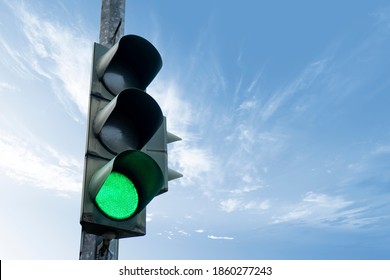 Traffic light in green color, with a blue sky and cloud in the background. - Shutterstock ID 1860277243