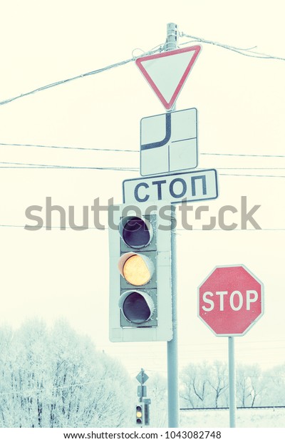 A traffic light with a\
green signal and a stop sign in winter. The inscription in Russian\
\