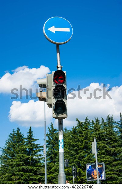 Traffic\
light with green trees and blue sky with clouds\
