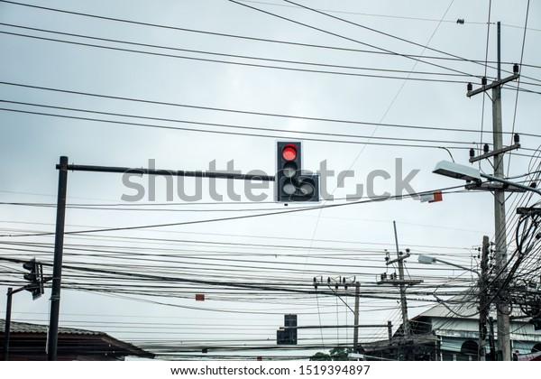 Traffic light at intersection roads showing red\
light with tangle of Electrical cables and Communication wires on\
electric pole.