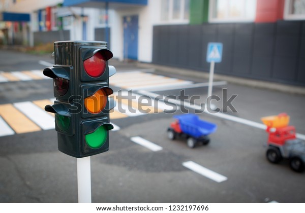 Traffic light on background of road and\
pedestrian crossing in city. Red, yellow and green traffic light.\
Car moving on road. Dividing strip on highway. Traffic Laws,\
blurred background,\
copy-space
