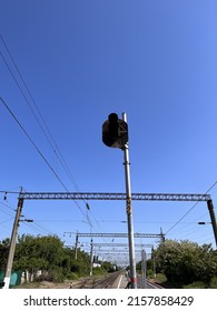 A traffic light at the railway station. A light for trains on the platform. A stoplight against wires and blue sky - Shutterstock ID 2157858429