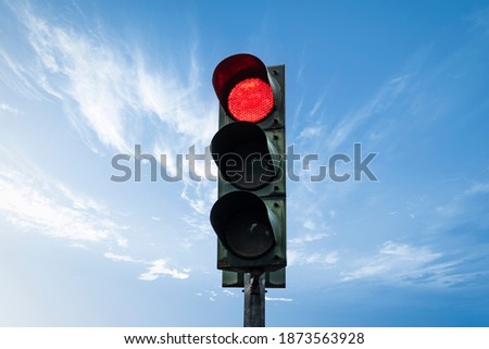 Traffic light in red color, with sky background.