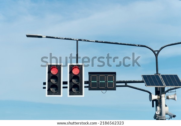 Traffic light red color two way with numeric light\
board. hanging on a steel arm protruding from the pillar. Install\
lighting lamps with solar panels. under the blue sky and white\
clouds at days.