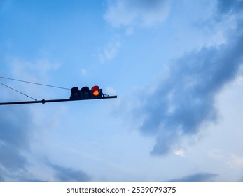 Traffic light with red semaphore lights, against a background of clear sky and white clouds - Powered by Shutterstock