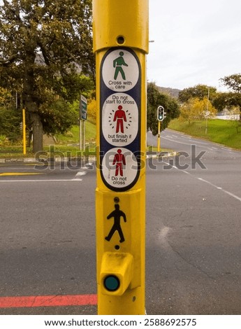 traffic light yellow pole displaying stickers, signs, signage on how to cross a road correctly by using the green or red man concept road safety for pedestrians