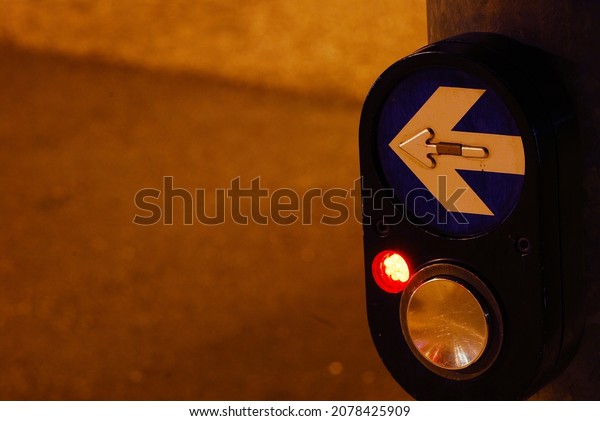 A traffic lightbutton with an arrow with left\
direction in a street