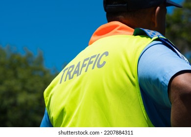 Traffic Officer, Non Recognisable, Wearing High Visibility Vest With His Back Or Rear To Camera And Selective Focus On The C And Blurry Face And Background