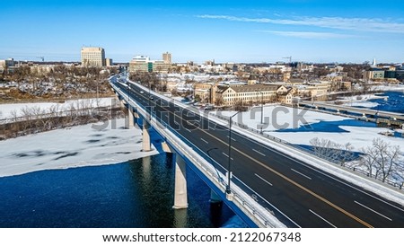 Traffic over the bridge that heads into the city - appleton, wisconsin usa. Old buildings off to the side showing history.