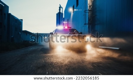 Traffic Patrol Car in Pursuit through Industrial Area. Police Officers Driving Squad Car, Chase Suspect on Industrial Road, Sirens, High Speed. Cops Emergency Response. Cinematic Action in