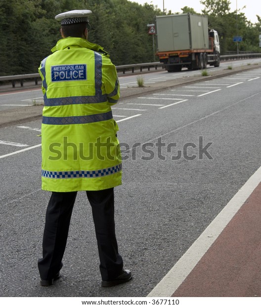 Traffic police officer waits standing in the\
road looking for on coming\
vehicles