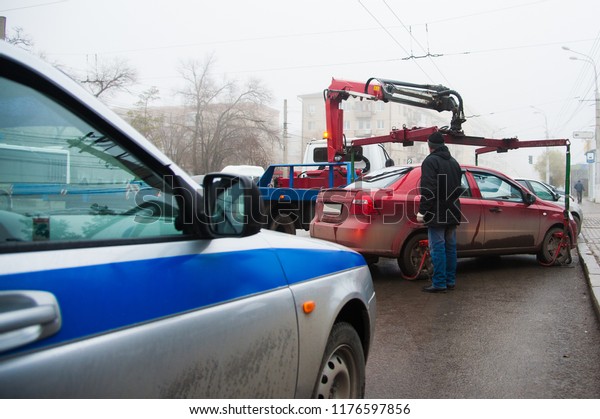 Traffic police officers on the street lifting\
the car on the tow truck for taking\
away