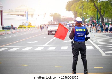 The traffic police in Thailand carry the red flag to provide traffic signals to the public: The Thai alphabet reads ja-raa-jon,krohng gaan, pra raat dam-ri, Translated English(Royal Initiative Project) 