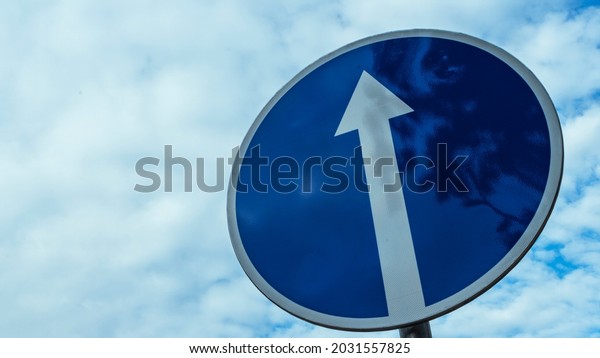 Traffic road sign straight ahead on cloudy\
blue sky background.