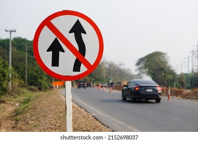 Traffic road sign with symbols of arrows to warn drivers do not overtake that can cause car accidents beside the rural road.                                        