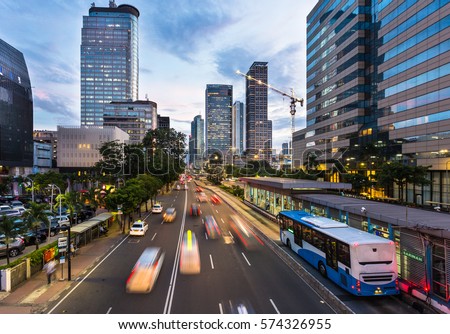 Traffic rushes in Jakarta business district along the city main avenue Jalan Thamrin at sunset in Indonesia capital city. The Transjakarta bus system enjoys its own traffic lane to avoid congestion.