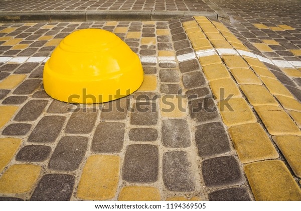 Traffic safety speed\
bump on the road from stone blocks. A yellow stripe speed ramp.\
Yellow concrete barrier
