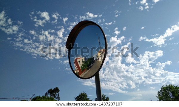 Traffic sign in a curved mirror\
to see the traffic on a lamppost along the road in the\
urbanization
