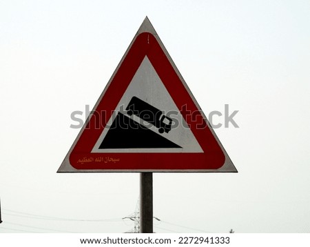 A traffic sign danger steep slope ahead, a truck on a downhill signal, caution for vehicle drivers to beware of a steep slope in front of you on the highway, selective focus of informative board
