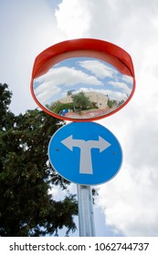 A Traffic Sign Directing To A Two Way Street, With A Traffic Mirror Above It