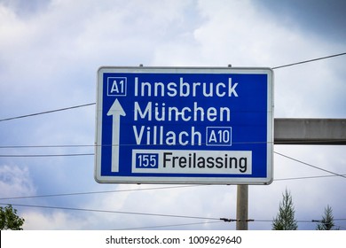 Traffic sign of direction to 1 highways in the Innsbruck, Munich,Munchen, Villach, Freilassing on cloudy summer sky background. Salzburg, Austria