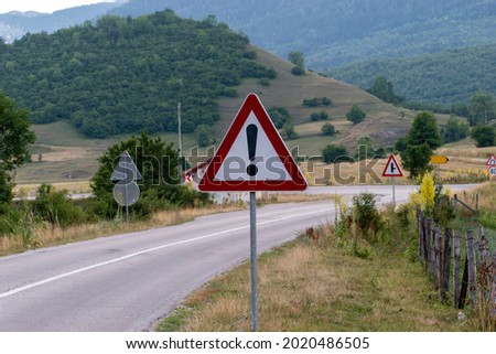 A traffic sign, exclamation mark. Warning road sign with an exclamation mark in red triangle on mountain highway.