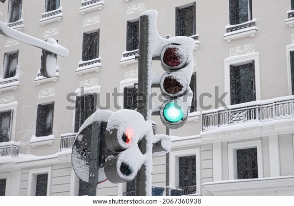 Traffic sign of a green traffic light covered with\
snow on a snowy winter\
day
