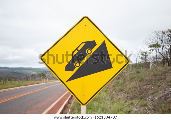 Traffic sign indicating steep descent on the paved\
road. Danger on the\
road.
