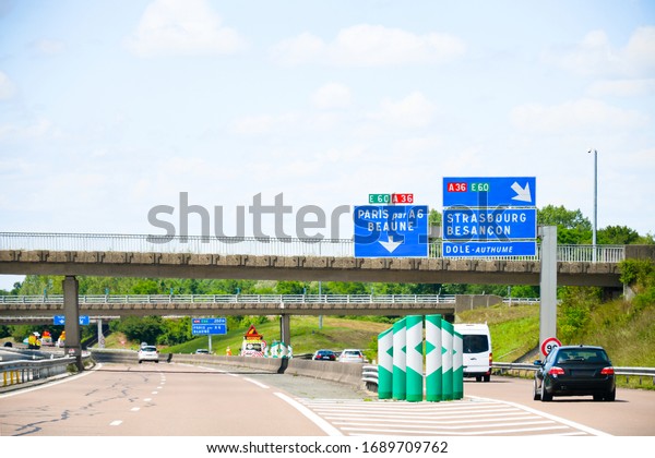 Traffic sign on the highway, toll or autoroute\
in France with big sqaure blue board ,road  number A36 direction to\
Paris ,Strasbourg city\'s names in french language . Transport and\
sign concept.