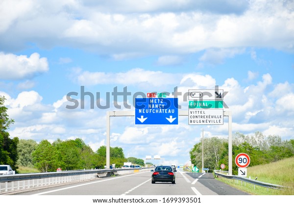 Traffic sign on the highway, toll or autoroute\
in France with big sqaure blue board ,road  number A31 direction to\
Metz ,Nancy, Neufchateau city\'s names in french language .Transport\
and sign concept.