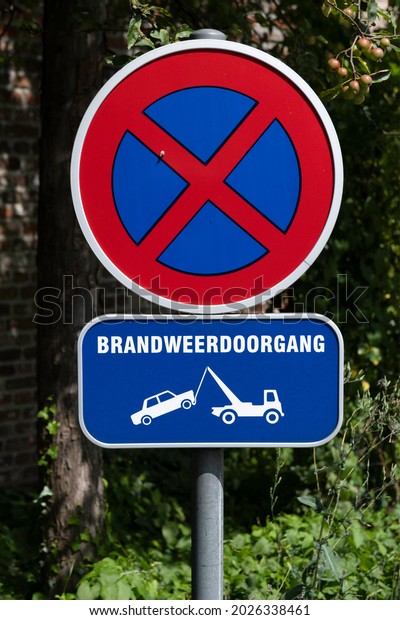 Traffic sign on pole with Dutch text \
\'Brandweerdoorgang\' (Fire brigade Passage), no parking. Pictogram\
of car being towed in the Belgian city of\
Leuven