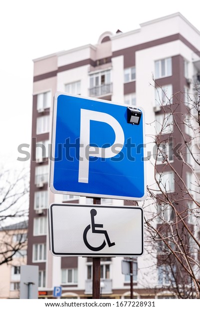 Traffic sign parking\
space for wheelchair users and disabled drivers in redidential\
area. Blue fill with white text. Capital letter P and carriage sign\
for disabled people
