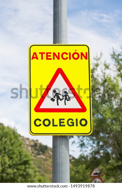 Traffic signal: Attention, school. Drive with\
caution. Spain.