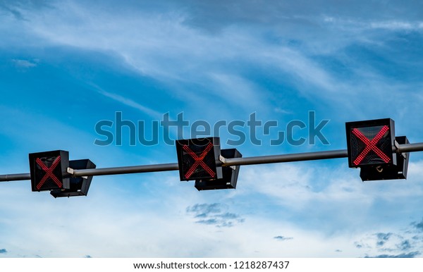 Traffic signal light with red color of cross sign on\
blue sky and white clouds background. Wrong sign. No entry traffic\
sign. Red cross guidance stop go traffic signal light. Warning\
traffic light. 