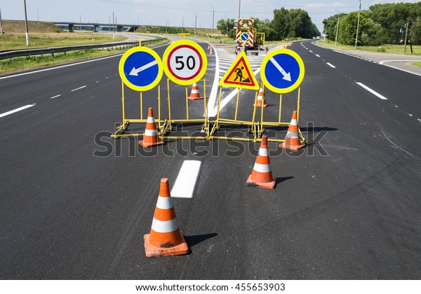 traffic signs during repair and paint work on the\
fenced road cones