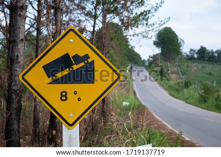 Traffic signs warning up to hill steep road sign to slope a steep climb 8 percent gradient in the road ahead at green grass in the backgroun